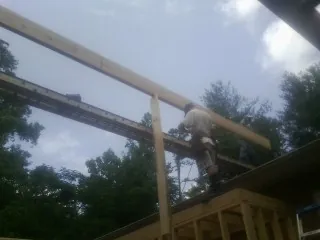 Carpenter setting a ridge beam over a new addition frame — Ice Dam Removal by Roofing Brothers in Hart