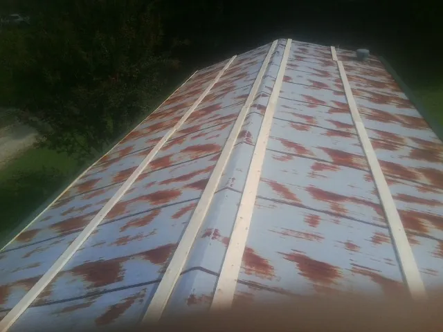 Rusted metal roof panels with new wood purlins before replacement — Storm Damage Roof Repair in Hart by Roofing Brothers