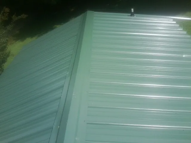 New green metal panels meeting at the ridge of a roof — Flat Roof Repair work by our crew in Hart