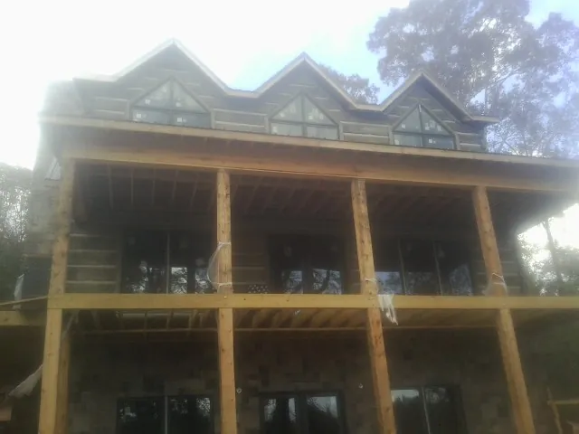 Dormers and porch framing on a large log home under construction — Roof Coating work by our crew in Hart