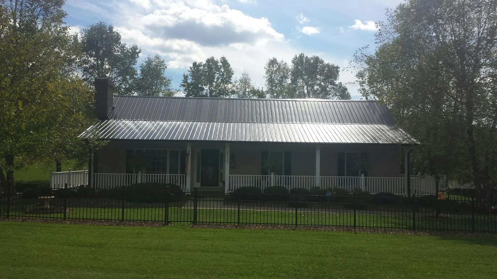 Gray metal roof on a brick ranch with a full width front porch — Gutter Guard Installation work by our crew in Hart